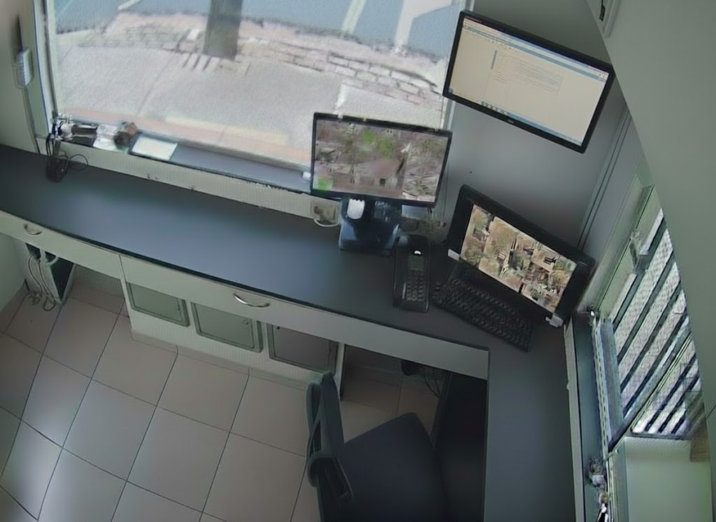 Sala de segurança com múltiplos monitores de computador exibindo feeds de câmeras de vigilância para monitoramento 24 horas do condomínio