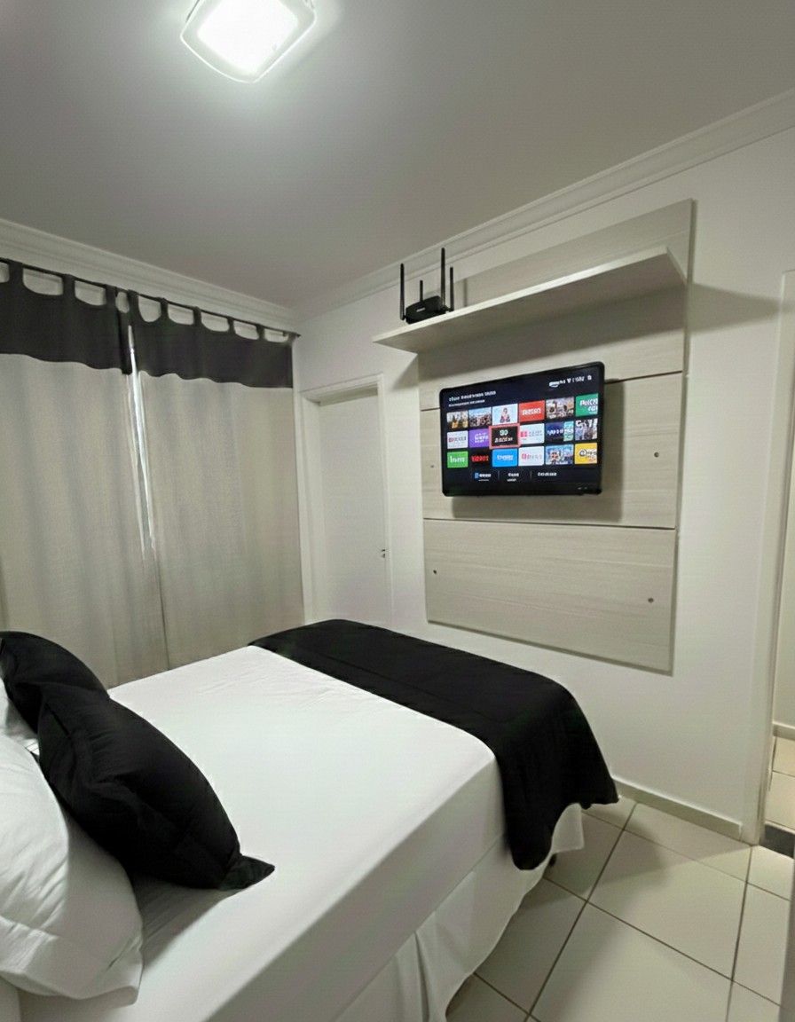 Quarto suíte elegante com banheiro anexo, armário embutido espelhado de 3 portas, ar condicionado, painel em madeira para TV com prateleira suspensa, mesa de canto integrada à cobertura com acabamento em vidro