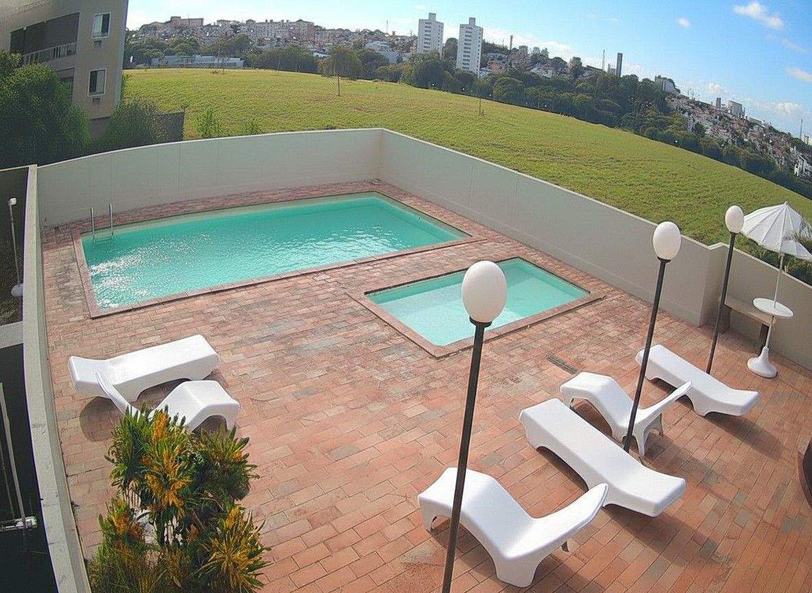 Área de lazer no rooftop com piscina, jacuzzi, espreguiçadeiras brancas e vista panorâmica deslumbrante da cidade